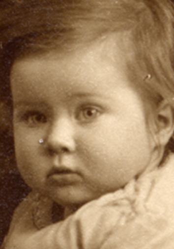 A close-up of baby's face shows the type of damage likely to be found on a print of this vintage.