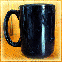 A deep blue coffee mug rests on a on wood table
