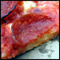 The focus is on this a curling bit of pepperoni in this filtered image of a pizza.